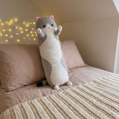 Grey Cloud Snug Cat long plush leaning on pillows on a cozy bed