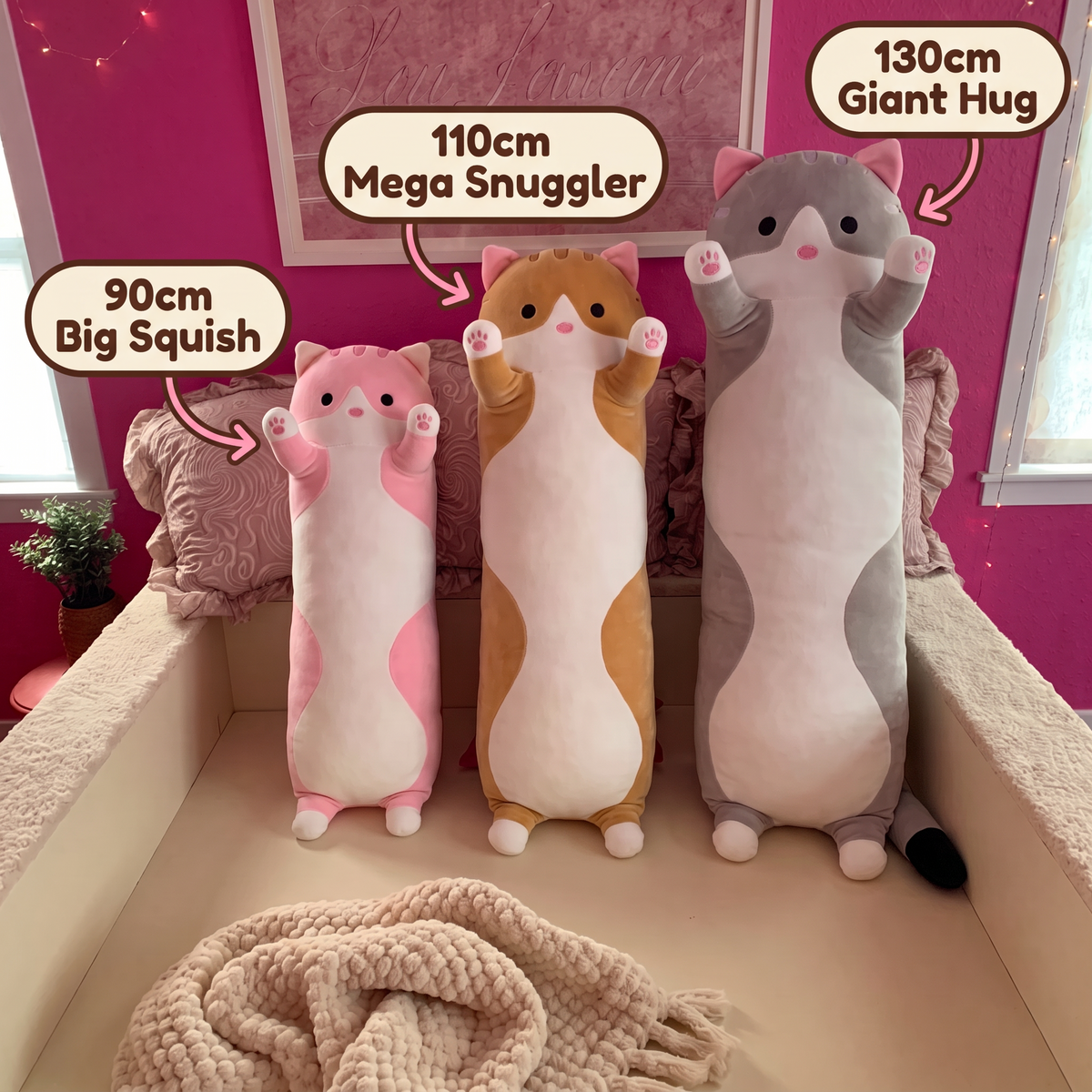 Three Snug Cats in different sizes and colours on a bed